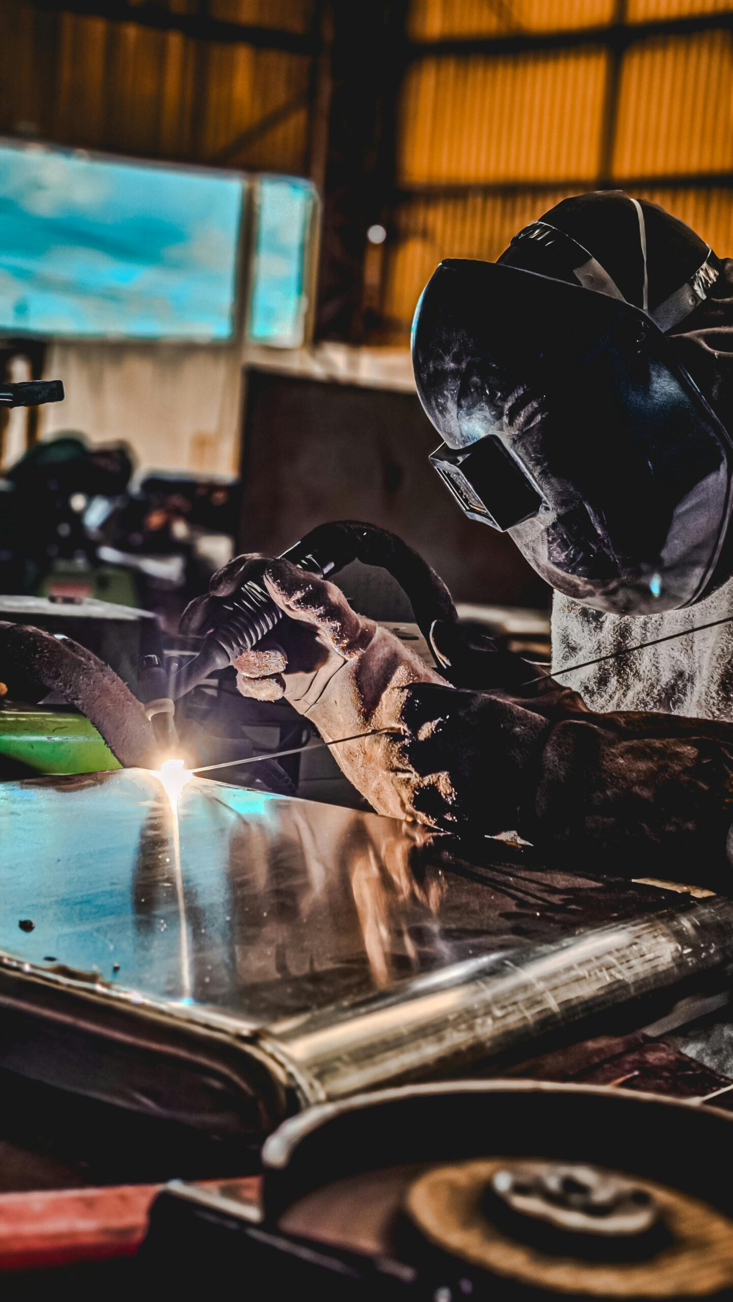 soldador profesional trabajando en chapa metálica con equipo de soldadura industrial