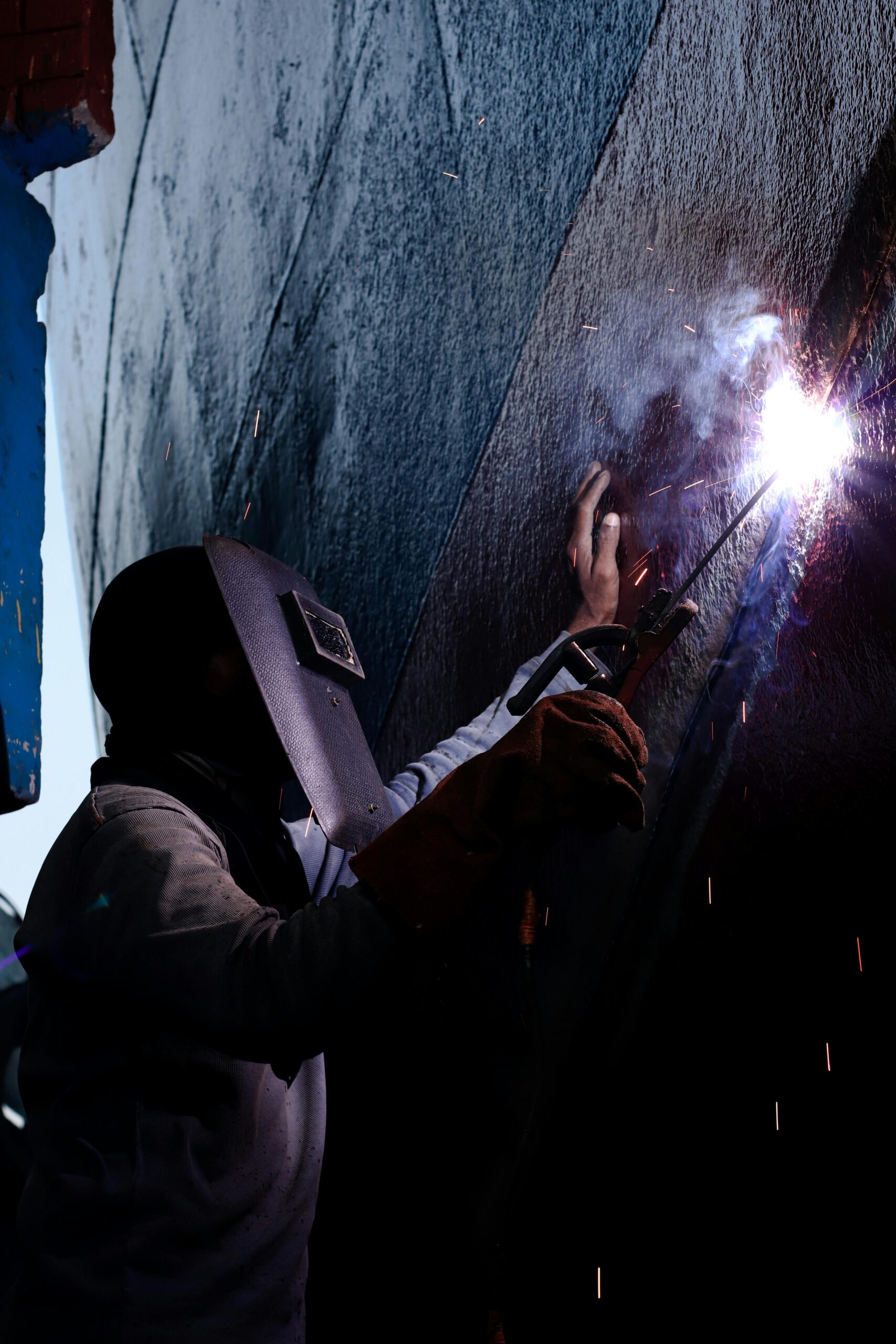 soldador realizando soldadura industrial en estructura metálica con equipo profesional